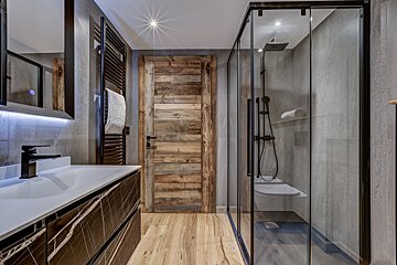 A bathroom with a wooden door and a glass shower