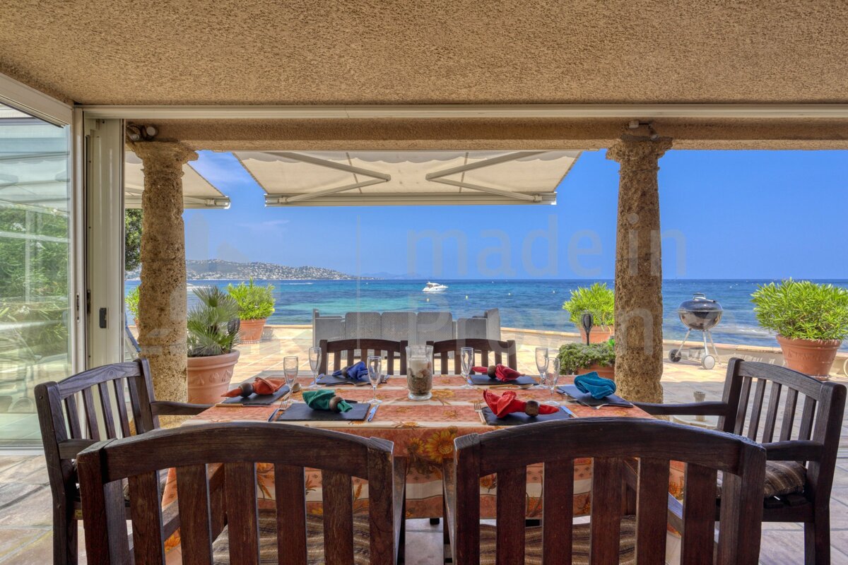 A table and chairs on a patio with a view of the ocean
