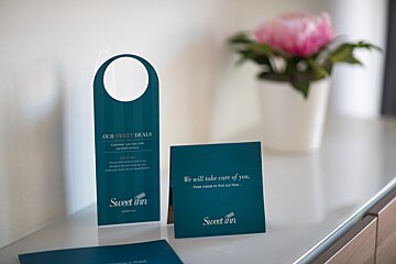 A sweet inn sign sits on a counter next to a flower