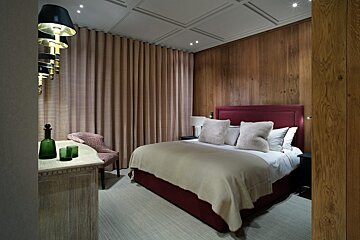 A bedroom with a bed a chair and a dresser