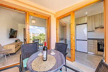 A bottle of wine sits on a table in front of a sliding glass door