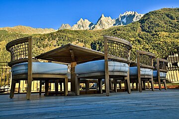 A table and chairs on a deck with mountains in the background