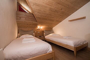 A bedroom with two beds and a wooden ceiling