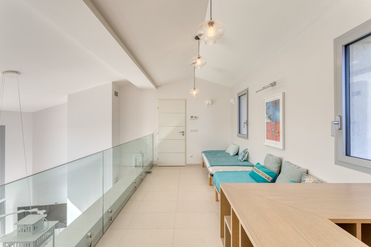 A hallway with a glass railing and a blue couch