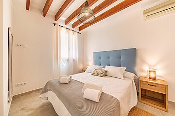 A bedroom with a blue headboard and white sheets