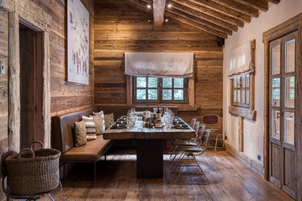 A wooden dining room with a long table and chairs