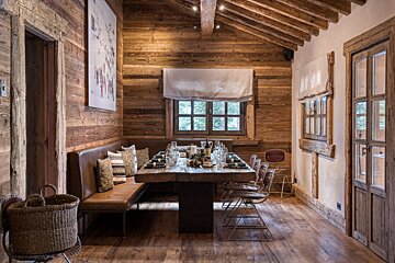 A wooden dining room with a long table and chairs