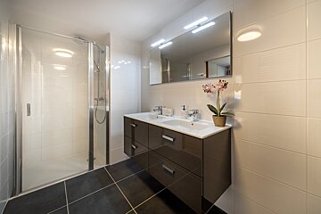 A bathroom with two sinks and a walk in shower