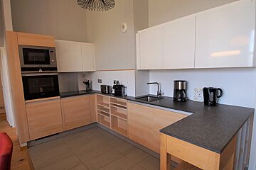 A kitchen with wooden cabinets and a black counter top
