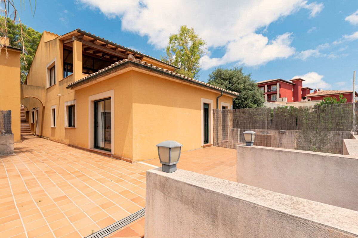 A yellow house with a red building in the background
