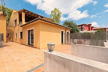 A yellow house with a red building in the background