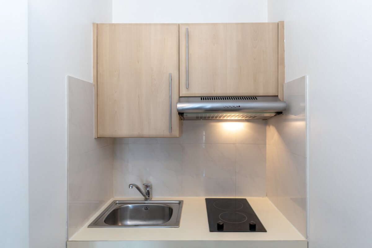 A small kitchen with a stove top oven and a sink