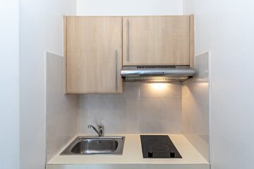 A small kitchen with a stove top oven and a sink