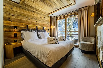 A bedroom with a large bed and a chair