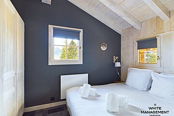 A bedroom with a white management logo on the corner
