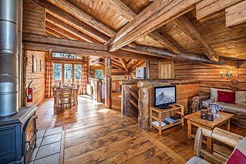 A living room in a log cabin with a flat screen tv