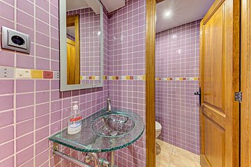 A bathroom with purple tiles and a glass sink