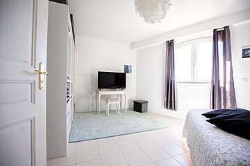 A bedroom with a flat screen tv on a desk