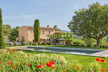 A large stone house with a large swimming pool in front of it