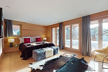 A bedroom with a large bed and lots of windows