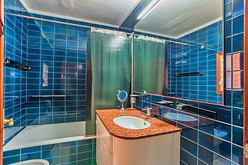A bathroom with blue tiles and a green shower curtain