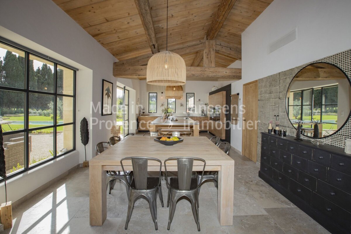 A dining room with a table and chairs and a sign that says maison lanssens provence immobilier