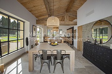 A dining room with a table and chairs and a sign that says maison lanssens provence immobilier