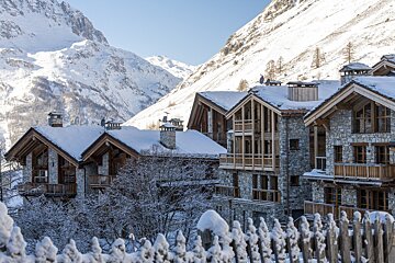 A row of snow covered buildings with mountains in the background