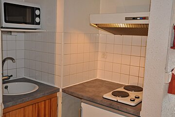 A small kitchen with a stove top oven and a microwave