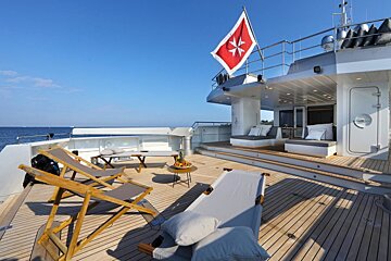 A large yacht has a red flag with a cross on it