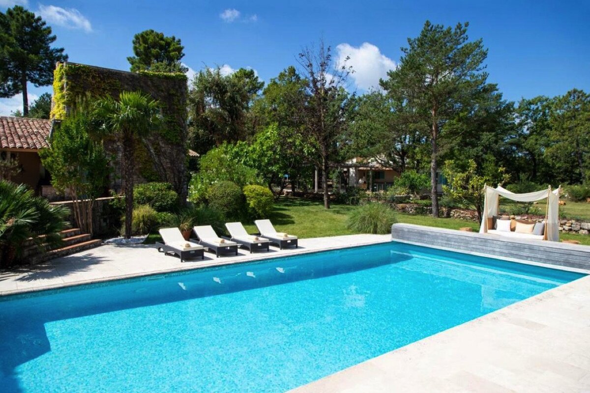 A large swimming pool surrounded by chairs and a canopy