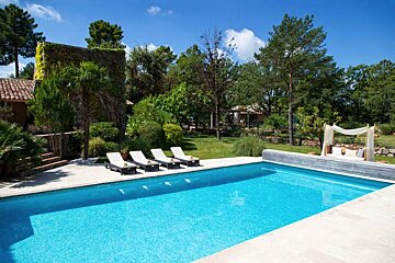 A large swimming pool surrounded by chairs and a canopy