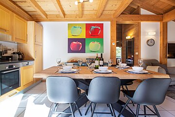 A painting of apples hangs above a dining table