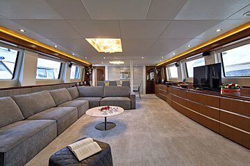 A living room with a couch and a book on the ottoman