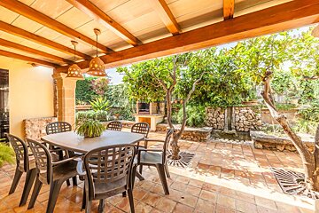 A patio with a table and chairs under a wooden roof