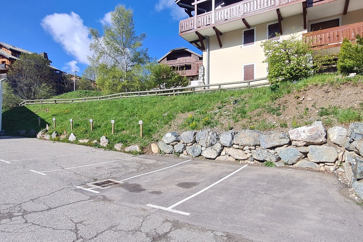 A parking lot with a stone wall and a building in the background