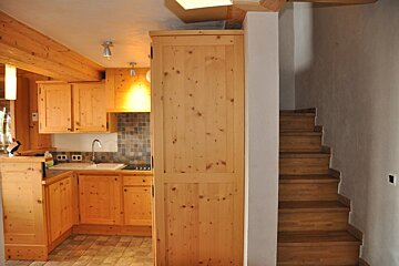 A kitchen with wooden cabinets and stairs leading up to it