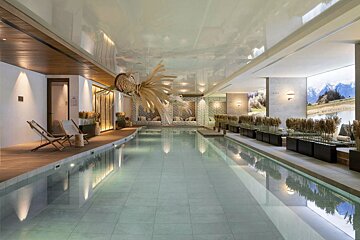 A serene indoor pool featuring modern design, warm lighting, natural dried grass decor, and wall murals depicting a mountain landscape, creating a calming spa atmosphere.
