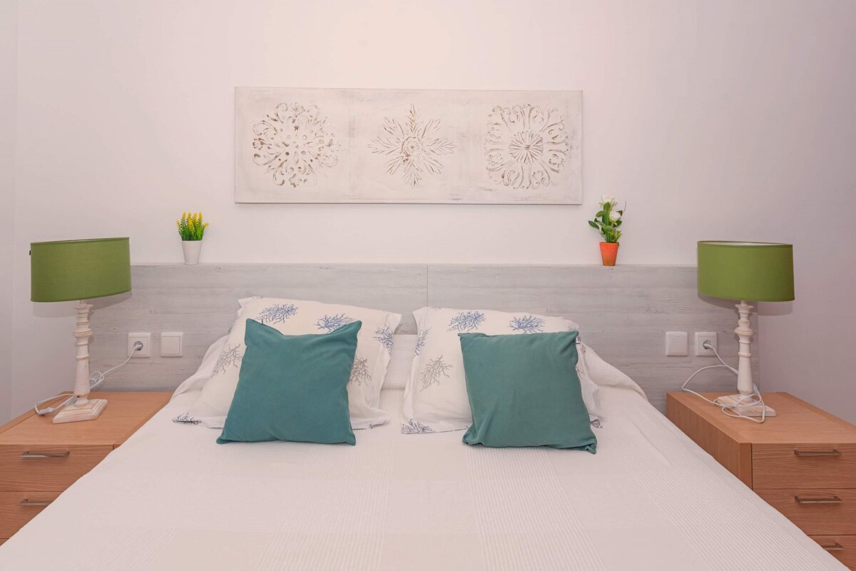 A bedroom with a painting on the wall above the bed