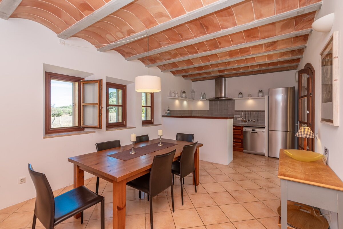 A dining room with a table and chairs and a refrigerator