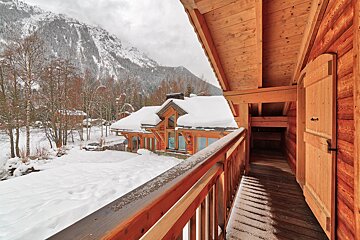 A wooden balcony overlooking a snowy mountain range