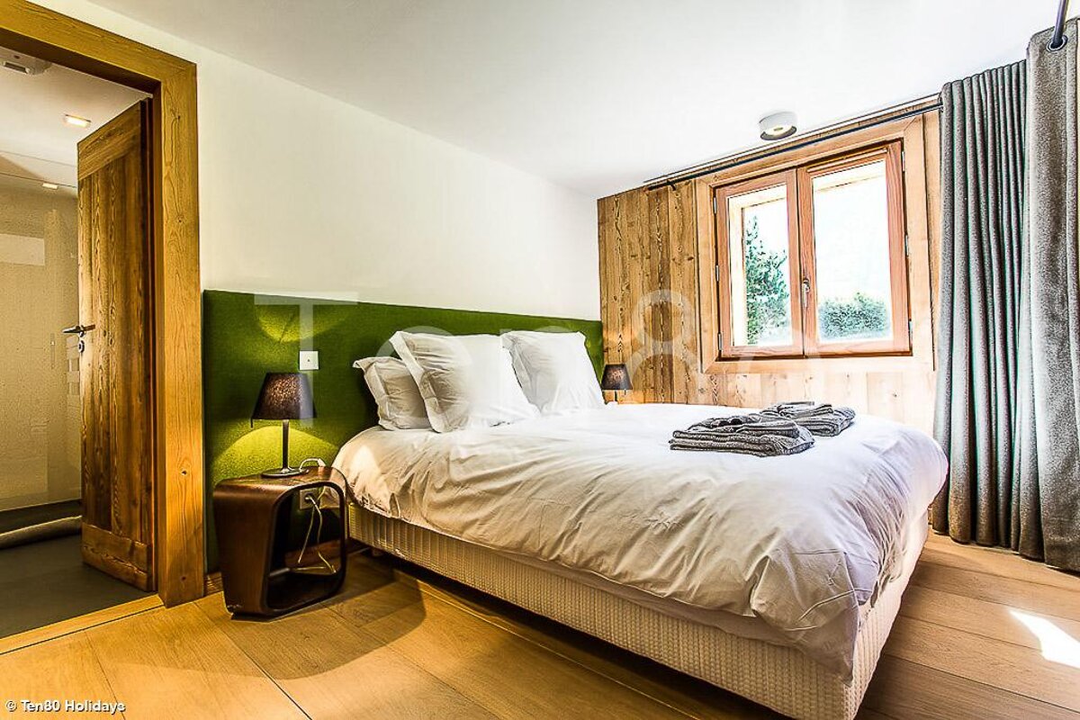 A bedroom with a large bed and a green headboard