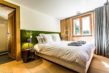 A bedroom with a large bed and a green headboard