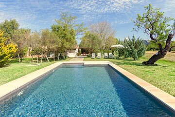 A large swimming pool surrounded by lawn chairs and trees