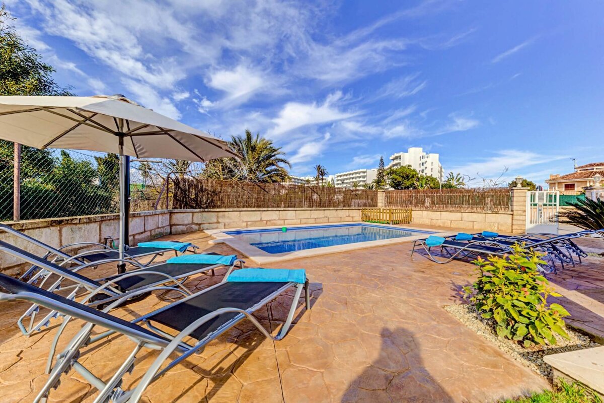 A swimming pool surrounded by chairs and a white umbrella