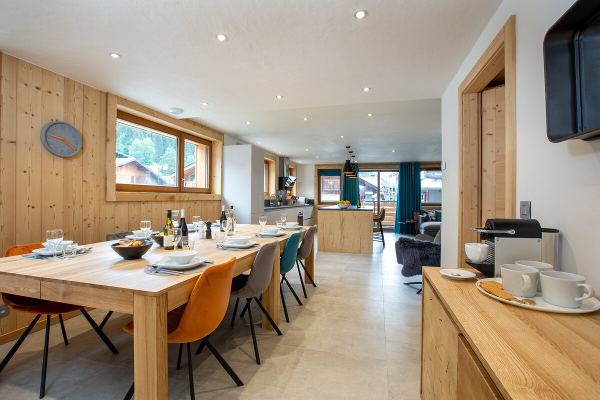 A dining room with a table and chairs and a clock on the wall