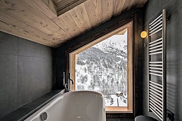 A bathtub in a bathroom with a view of snowy mountains
