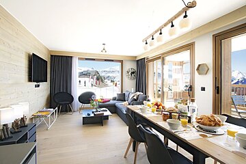 A living room with a table and chairs and a clock on the wall