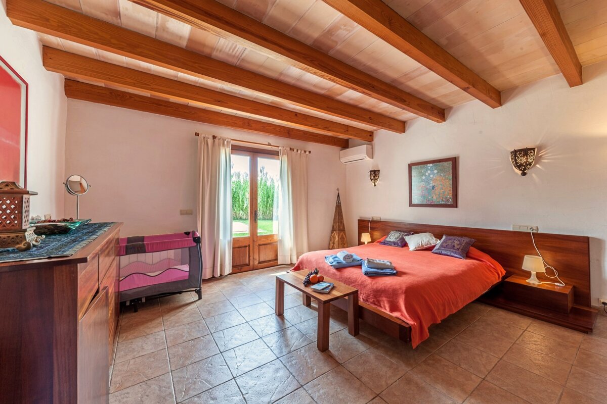 A bedroom with a large bed and a pink crib
