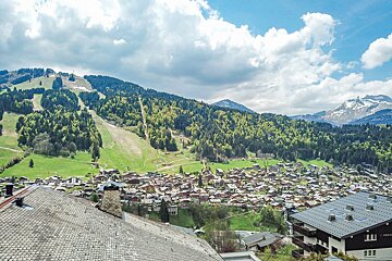 A view of a small town in the mountains with a ski lift in the background
